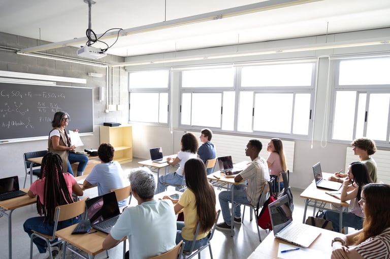 Mature female teacher explaining lesson to multiracial high school students in class